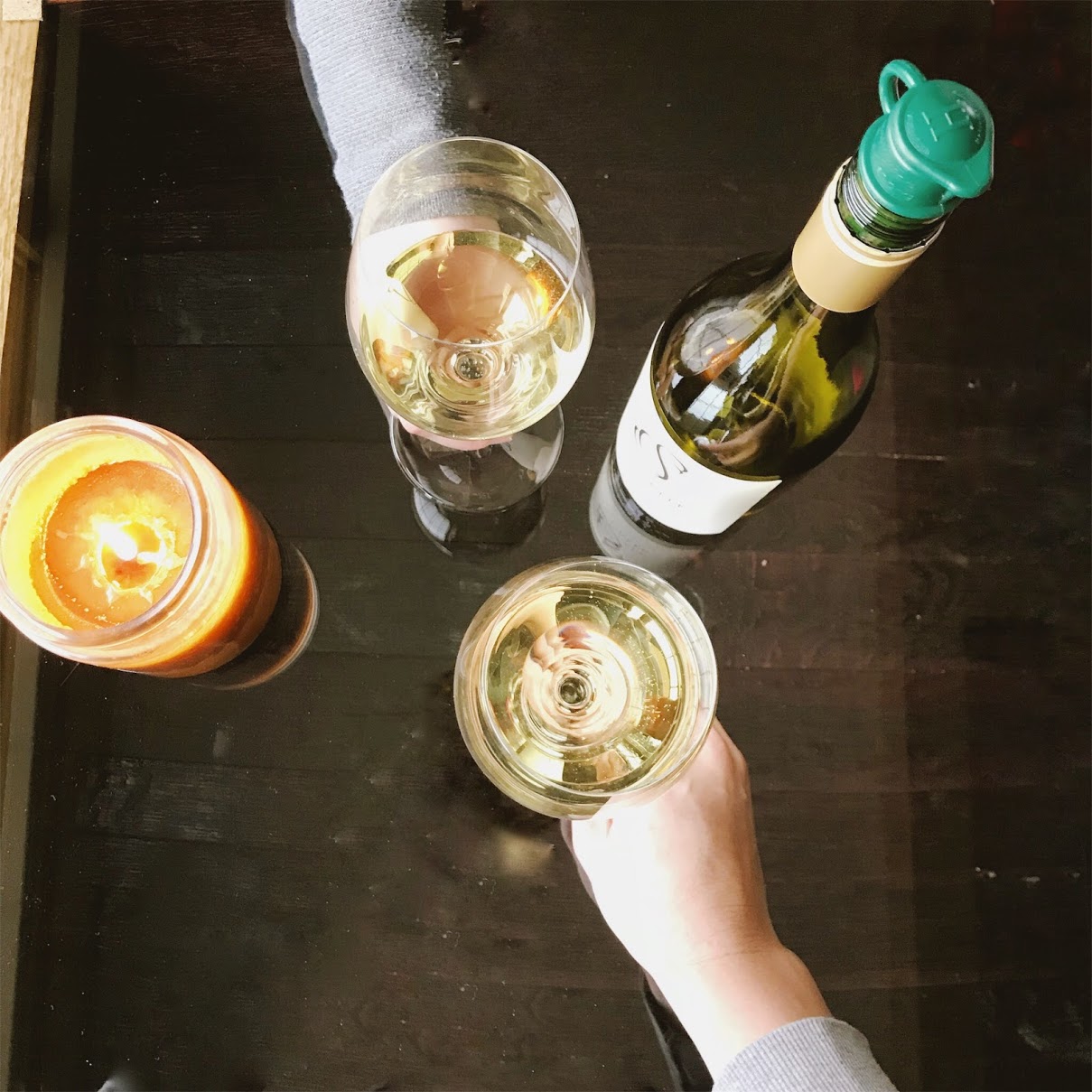 Overhead view of a Soldier Creek Winery wine bottle, two wine glasses, and a candle on a dark table