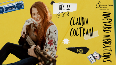 “Event poster for Claudia Coltrain at Soldier Creek Winery’s Vineyard Vibrations on December 12 from 6–8PM. Claudia smiles while playing guitar, wearing a floral blouse, with a cheerful retro design including cassette tapes and a blue boombox.”