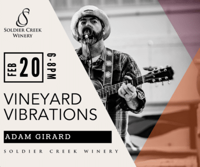 Black and white photo of Adam Girard in a plaid shirt and cowboy hat, singing and playing guitar. Graphic promotes Vineyard Vibrations at Soldier Creek Winery on Feb 20 from 6–8 PM.