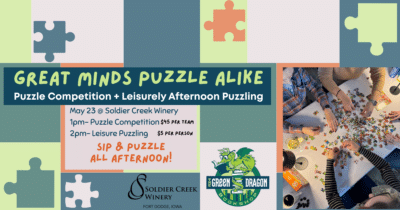 Promotional graphic for "Great Minds Puzzle Alike" at Soldier Creek Winery on May 23 — puzzle competition at 1pm ($45/team) and leisure puzzling at 2pm ($5/person), co-hosted with The Green Dragon Bookshop. Overhead photo shows multiple people assembling a colorful puzzle with wine glasses nearby. Puzzle piece illustrations on a green and teal background.